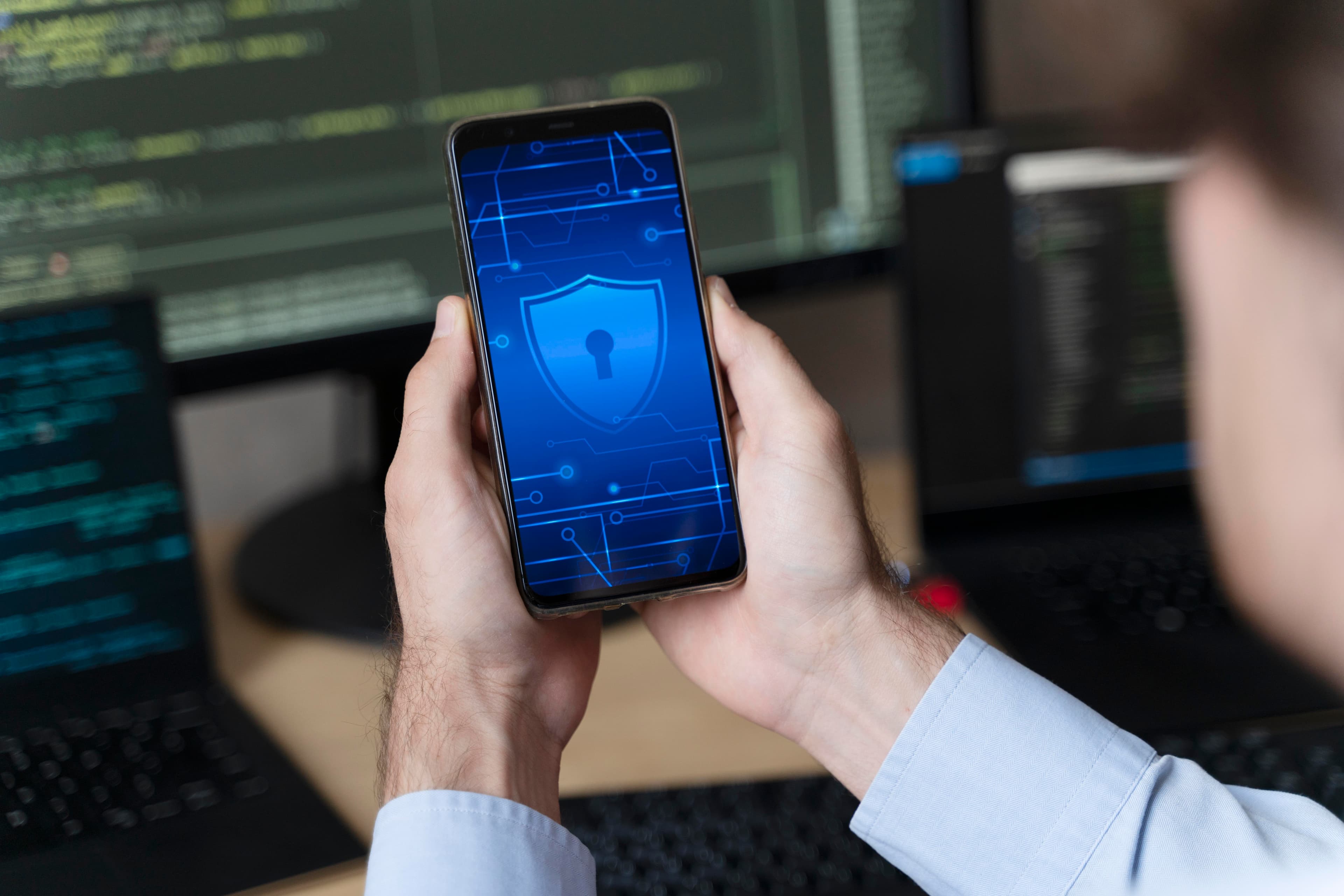 Smartphone displaying a security shield icon in front of a code screen
