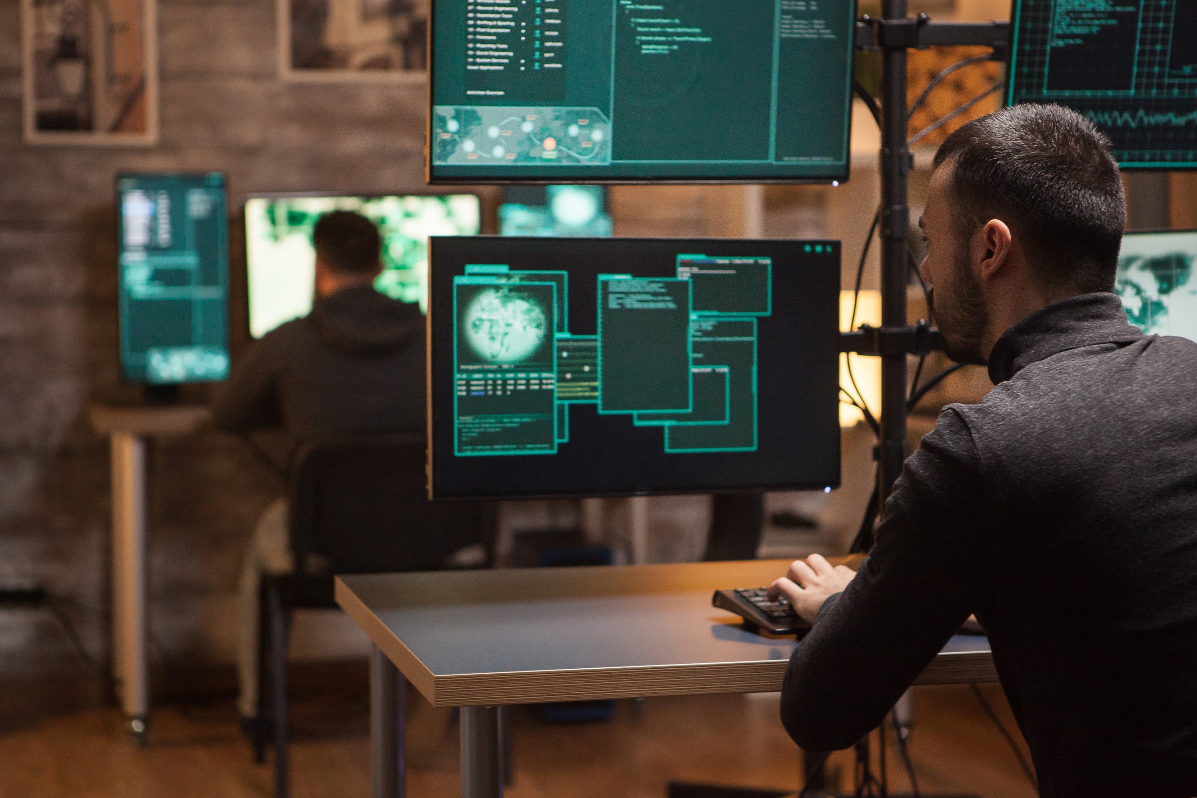 Analyst in front of multiple screens displaying code and data visualisations